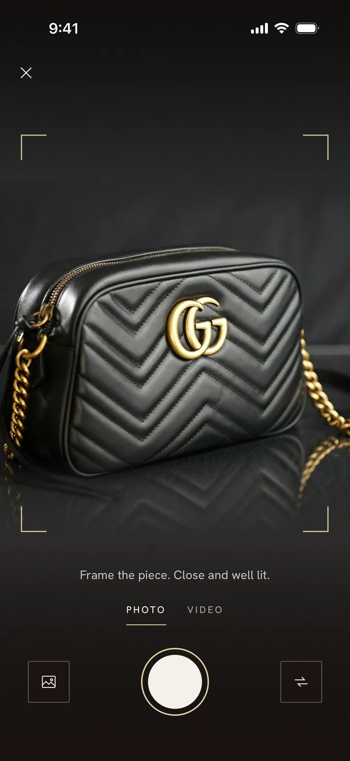 The camera, a black Gucci GG Marmont between its brackets.
